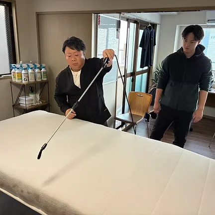 洗浄剤を吹き付ける実演を行う講師と、それを見学するスタッフ